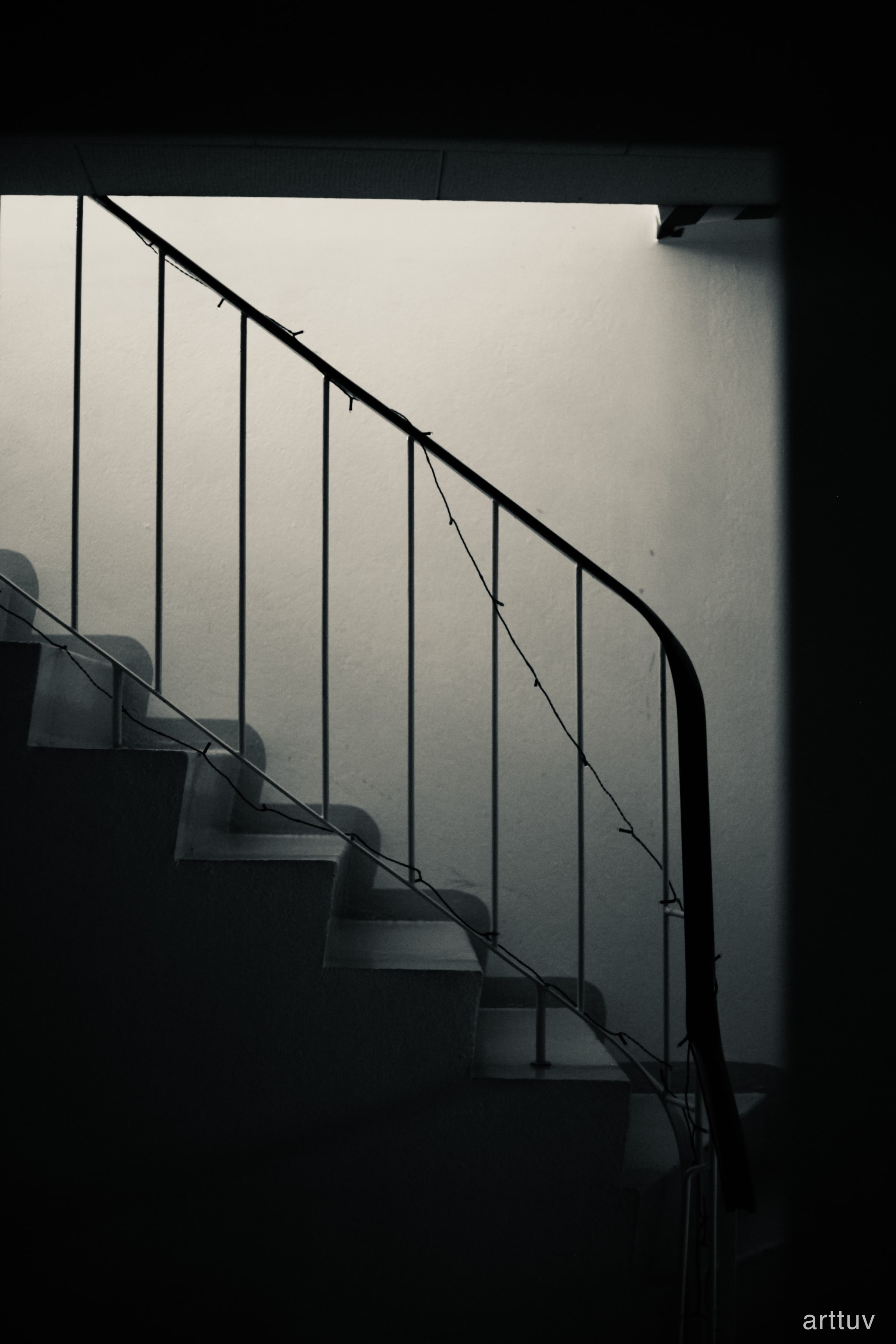 Black and white photograph of a stairway with a metal handrail.